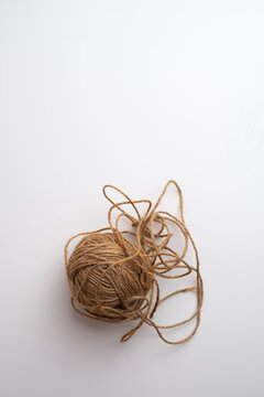 Tangled ball of brown jute twine with loose loops on white background, natural rope string for craft and packaging, copy space