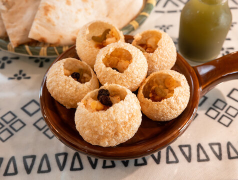 Traditional Indian panipuri golgappa snack served with mint flavored water.
