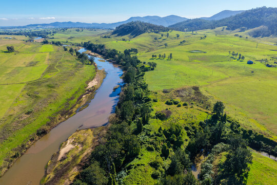 Aerial view of a river winding through green farmland and wooded hills in Lambs Valley, Hunter Valley, New South Wales, Australia.