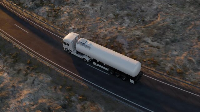 An elevated camera tracks a white tanker truck traveling along a dark asphalt road through rocky desert terrain, showing the length of the tank trailer from above.
