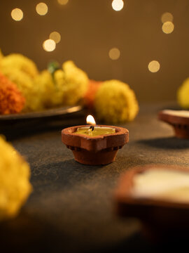 Traditional Clay Diya with a Lit Flame Against a Dreamy Warm Golden Bokeh Background, Festive Diwali Close-Up Shot

