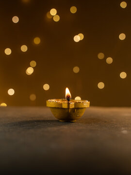 Four Traditional Clay Diwali Diyas with Flickering Flames Arranged on an Ornate Golden Patterned Surface, Warm Festive Close-Up Shot.