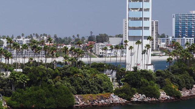 Aerial view gliding past the decorated oil production towers of Astronaut Islands, THUMS Islands off the coast of Long Beach, California, with beachfront condos in view.