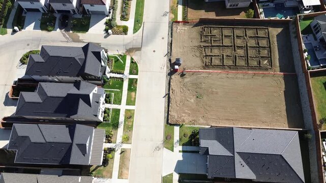 Tightly clustered residential rooftops border freshly surveyed construction building lots along Frisco. Concrete street paving contrasts against leveled clay soil ready for concrete, Texas