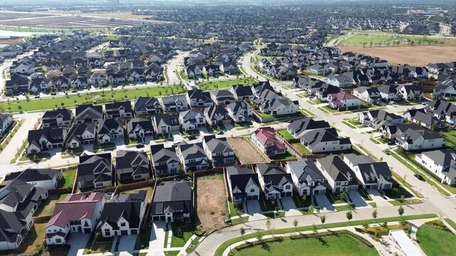 Wild shrubbery borders abandoned commercial parcel boundary lines toward distant horizons past active home construction areas along Frisco. Orderly residential streets define modern, Texas