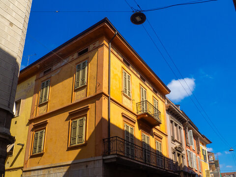 The yellow building features shutters, small balconies