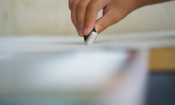 Little girl hand erasing a mistake with a rubber eraser.