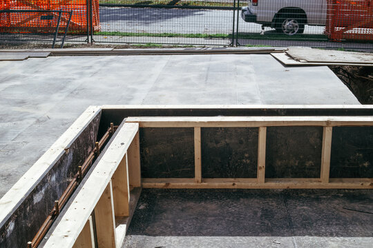 Wooden formwork and steel reinforcing bars for concrete foundation wall. Outdoor construction site with retaining wall framing and rebar. Waterproofing and structural repair concept. Selective focus.