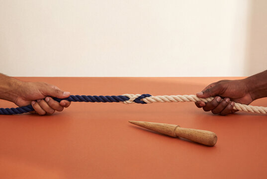 Navy and cream rope splice gripped by olive and deep brown adult hands, joining forces and multiethnic partnership
