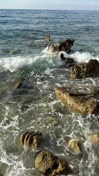 White Sea Foam and Waves Swirling Around Coastal Rocks in Slow Motion