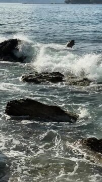 Sea Waves Crashing Over Coastal Rocks with Mountain Bay in Slow Motion
