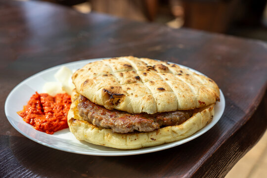Traditional Balkan pljeskavica grilled meat sandwich with ajvar and onions