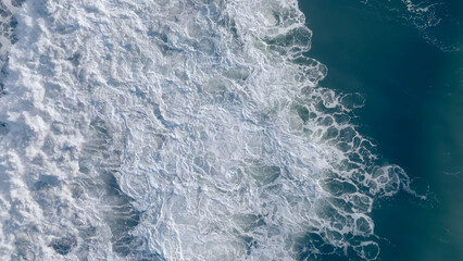 From above, ocean swells fan into pale foam along the dark volcanic sand of Khalaktyrsky Beach in Kamchatka Krai, Russia, creating a striking natural coastal pattern for travel and nature themes © TravelFlow