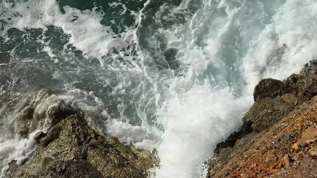Overhead View of Sea Wave Exploding in White Spray on Brown Rocks