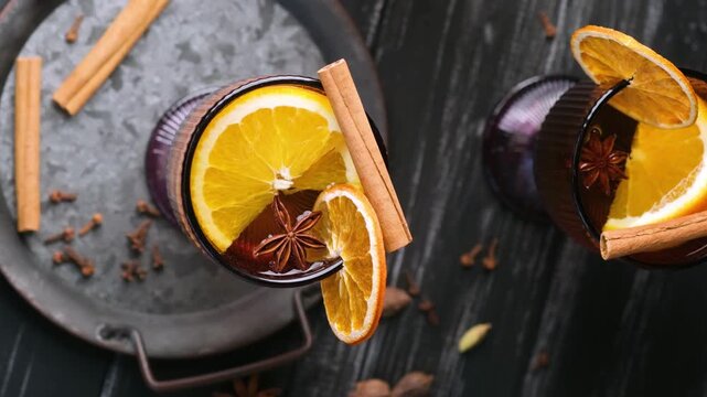 Warm spiced drink with orange slices and cinnamon sticks on dark background