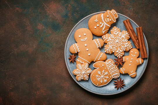 Close-up of Christmas gingerbread cookies on a plate on a dark rustic background, top view, flat lay, copy space.