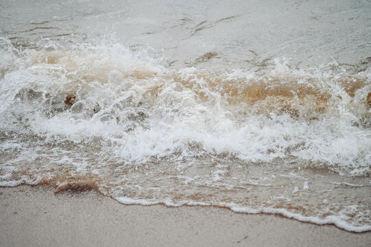 surf on sandy beach, strong waves, storm warning