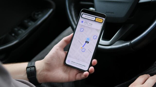 Driver uses a smartphone map to locate nearby car service centers, reflecting digital navigation, mobile roadside support and the growing demand for on-the-go vehicle maintenance.