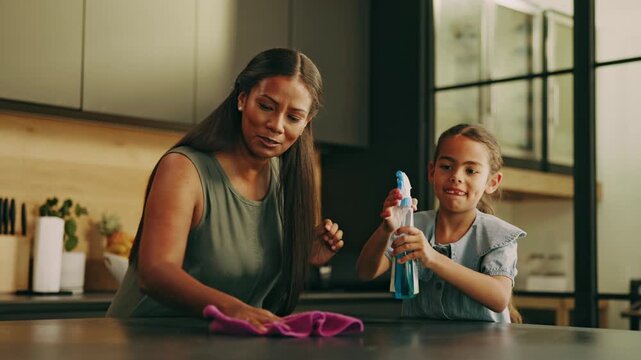 Mom, child and cleaning table with spray bottle in home for disinfection, hygiene or chores together. Happy mother, kid or helpful daughter wiping surface for dirt, germs or bacteria removal in house