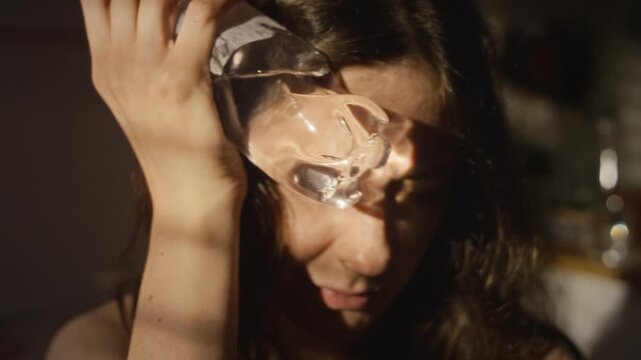 Caucasian young adult woman pressing cold water bottle against forehead relieving heatstroke symptoms. Footage suitable for healthcare advertising, summer wellness content, or pain relief promos