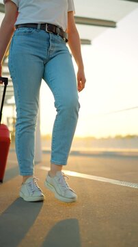 Woman confidently pulling a suitcase in an airport terminal. Slow motion.