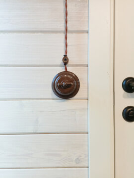 Closed door and vintage light switch on a white wooden wall