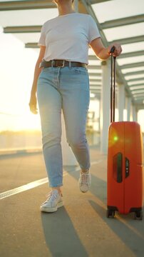 Woman confidently pulling a suitcase in an airport terminal. Slow motion.