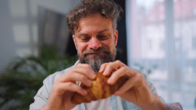 A man enjoying a fresh croissant for breakfast.
