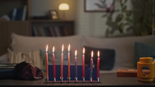 Colorful Hanukkah candles burning on menorah during Jewish holiday celebration at home. Footage ideal for cultural advertising, religious holiday promotions, and seasonal greeting videos