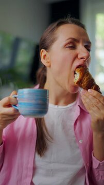Woman enjoying a fresh croissant and coffee for breakfast.