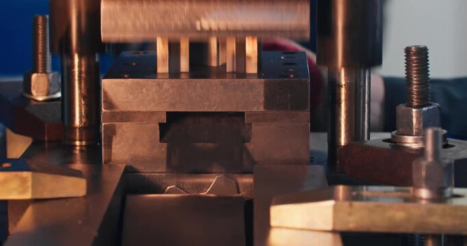 Mechanical stamping press producing metal parts in factory workshop. Industrial blanking process shown in close-up.