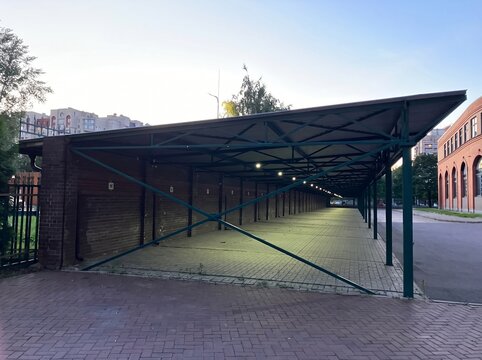 Long empty covered parking shelter with metal roof in urban courtyard