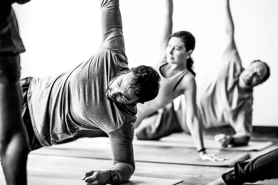 Black and white group yoga class practicing side plank