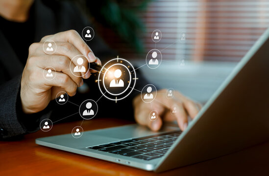 Business person using a pen to select a target candidate profile on a digital HR network screen with a laptop. Concept of talent acquisition, recruitment, and human resources management.