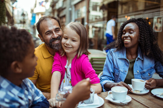 Father hugs daughter as family enjoys outdoor cafe