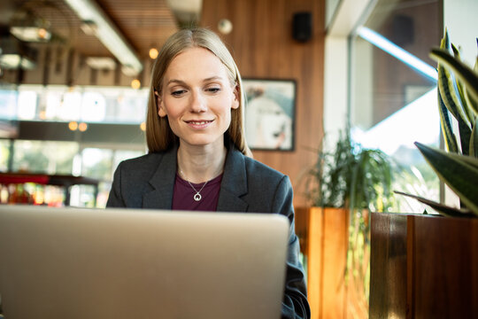 Smiling businesswoman working on laptop in cafe