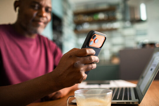 Man checking smartphone while working on laptop at home