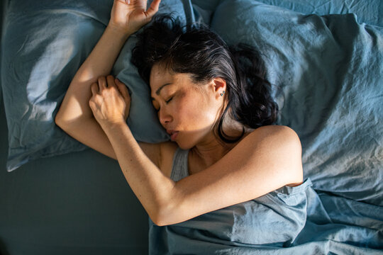 Woman sleeping on her side in bed at home