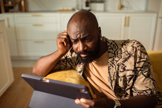 Worried man looking at tablet at home