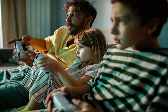 Man teaching children to play video games at home