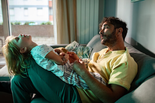 Father with daughter lying on his lap at home