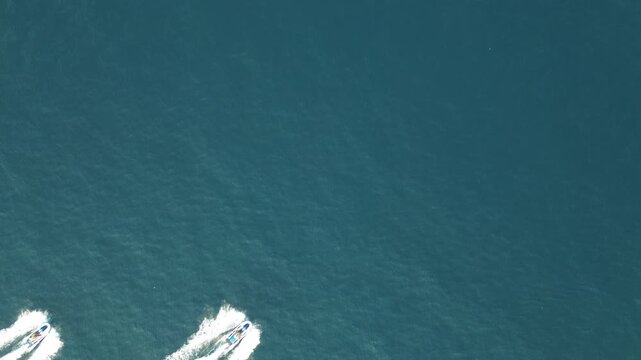 Static top-down drone shot of two jet skis crossing diagonally across the turquoise Adriatic Sea near Dubrovnik, Croatia, leaving white foam wakes behind them. Original unedited 4K clip.