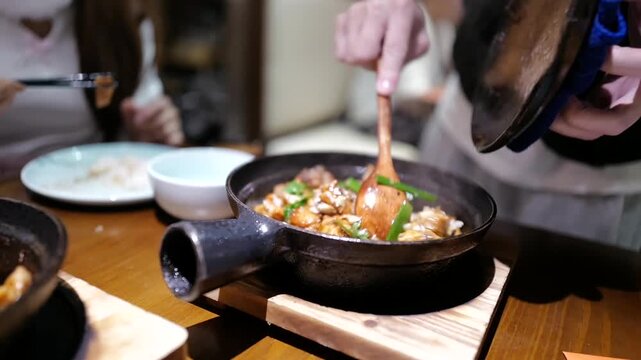 A clay pot dish filled with braised chicken, garlic, onions, green onions, and herbs, all seasoned with a savory sauce in Sanya, Hainan, China