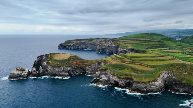 Wild Atlantic coastline of Sao Miguel, Azores, with volcanic cliffs dropping into deep ocean water. Remote island scenery shaped by erosion, waves and coastal agriculture