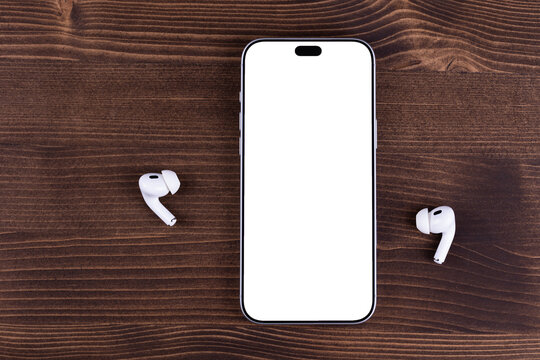 mockup iPhone 18 Pro Max smartphone with transparent screen with AirPods headphones on a wood table. Apple iPhone 18 Pro Max is a flagship smartphone by Apple. Batumi, Georgia - September 29, 2026