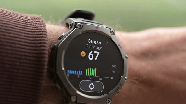 Close-up of rugged smartwatch on wrist showing stress level score and daily graph