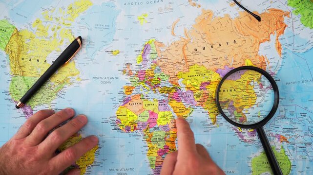 Male hand pointing at Arabian Peninsula on world map, illustrating strategic importance of Middle East for global oil supplies, energy markets, international trade, and economic stability