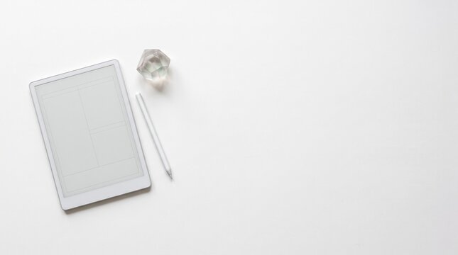 White tablet with stylus and crystal paperweight. Minimalist flat lay workspace with ample copy space for digital design and creative planning.