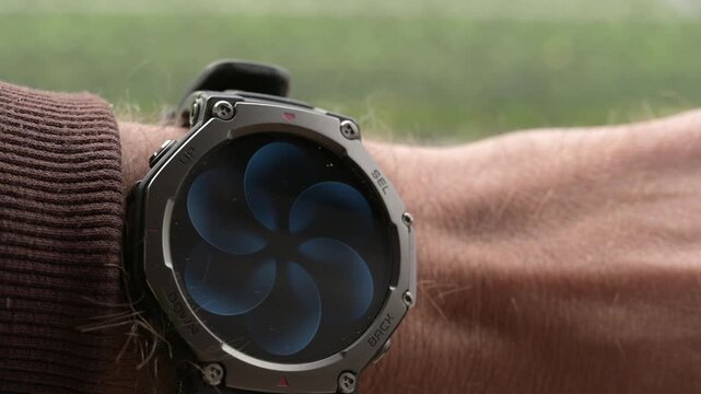 Close-up of rugged smartwatch on wrist showing breathing exercise animation screen