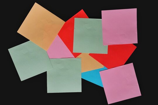 Colorful square origami papers scattered on a black background.